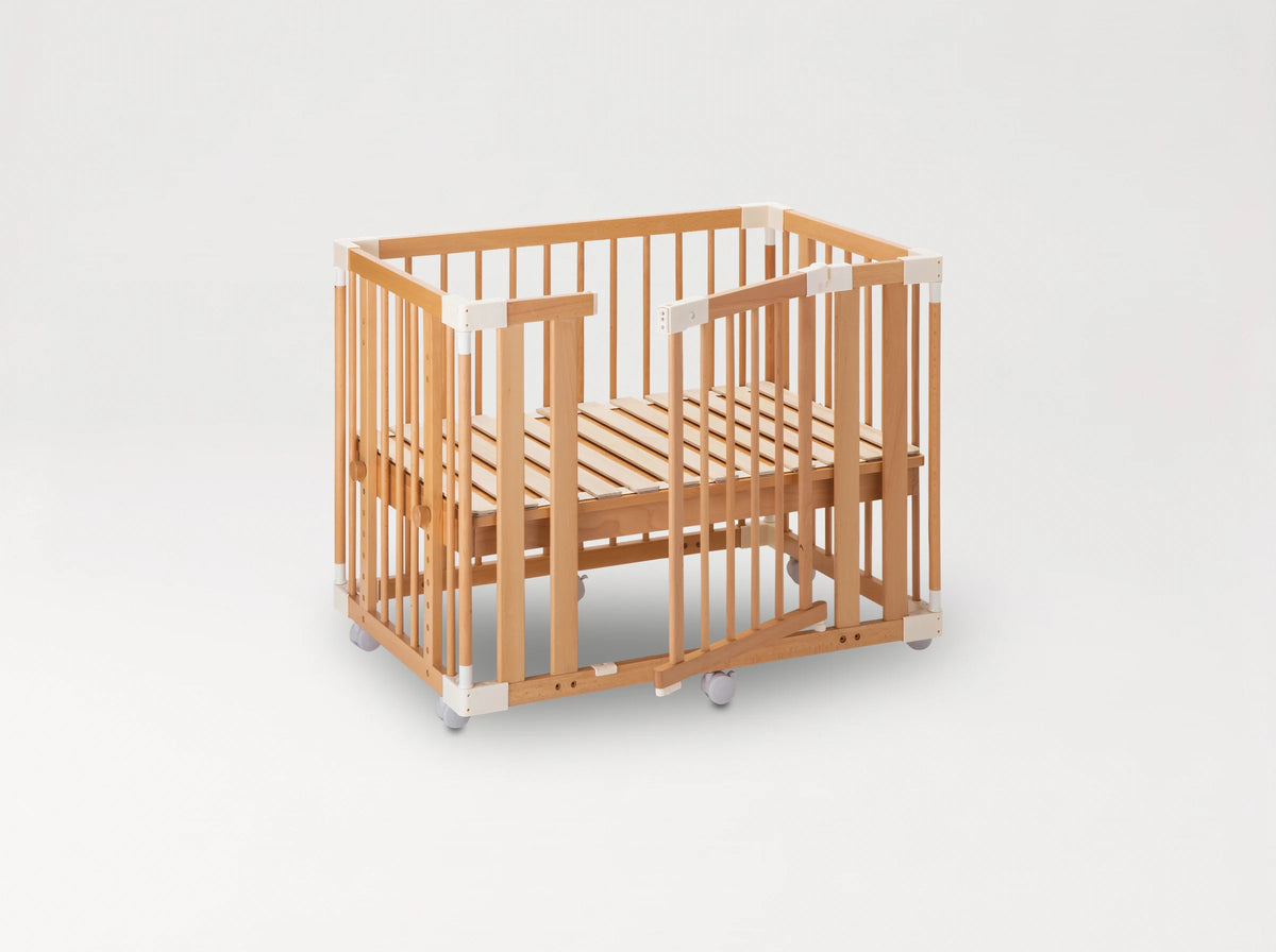 The färska Creative Cot as a cot: slatted base in the low position, the side gate open, on castors