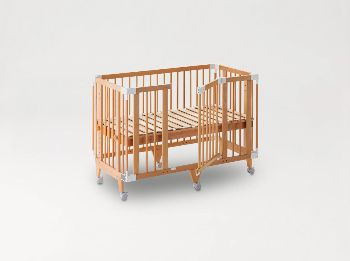 The färska Creative Cot Long as a cot: slatted base, the side gate open, on castors