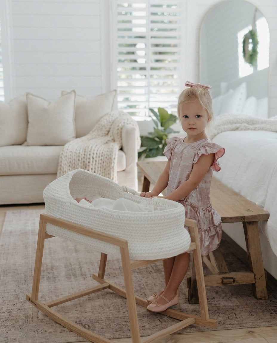 White handwoven Moses basket on a wooden stand in a bright bedroom