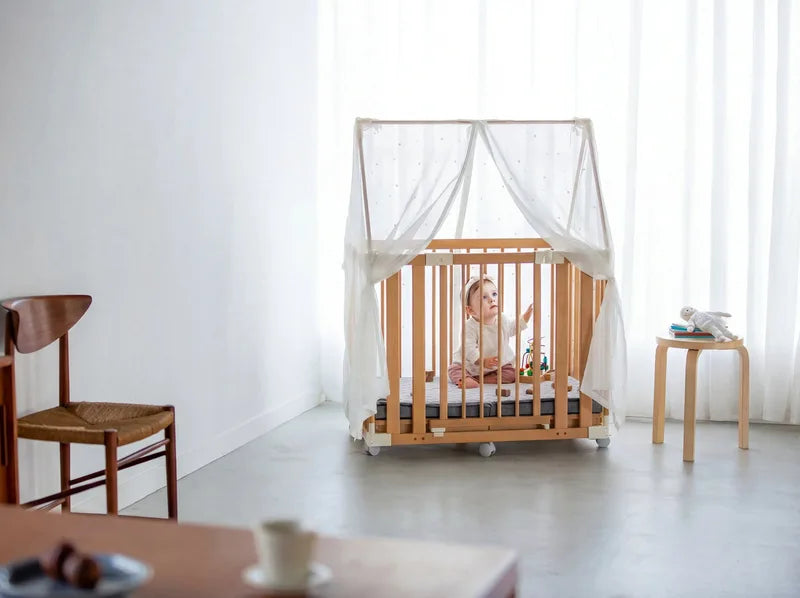 A baby playing in the Creative Cot playpen with a canopy
