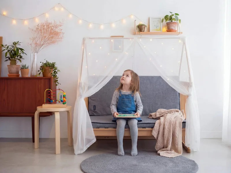 A little girl sitting on the Creative Cot sofa with cushions