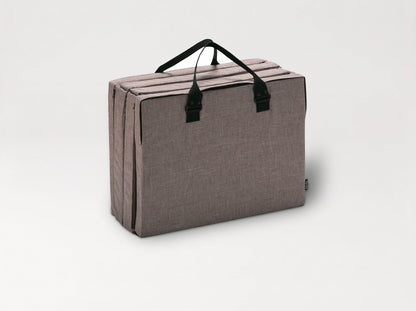 The Compact Bed Free in Melange Brown folded into its carry bag with handles 