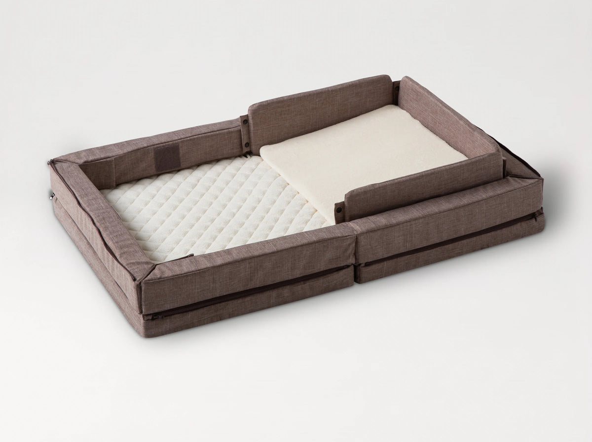 Compact Bed Free in Melange Brown in safety mode: padded sides raised all round the quilted mattress, with the wedge pillow 