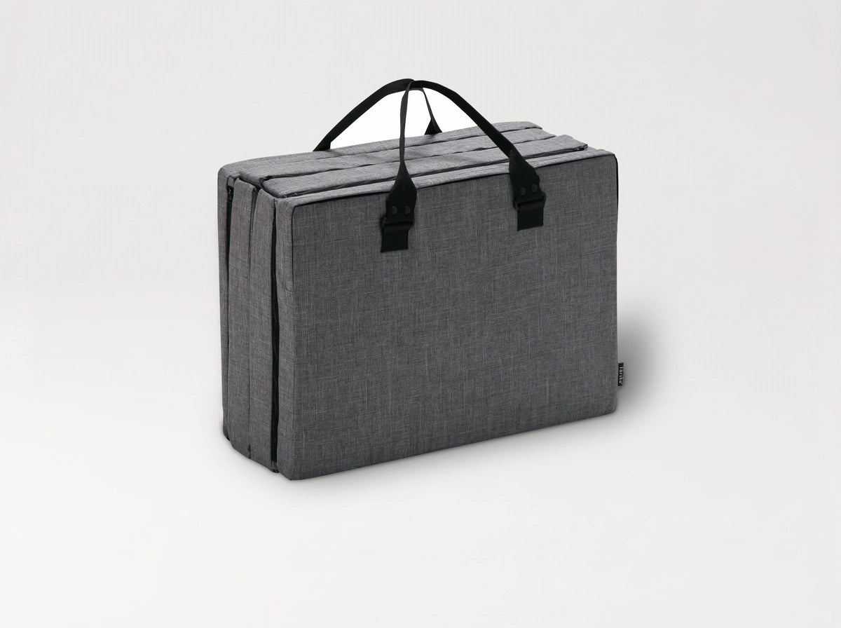 The Compact Bed Free in Melange Gray folded into its carry bag with handles 