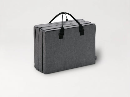 The Compact Bed Free in Melange Gray folded into its carry bag with handles 