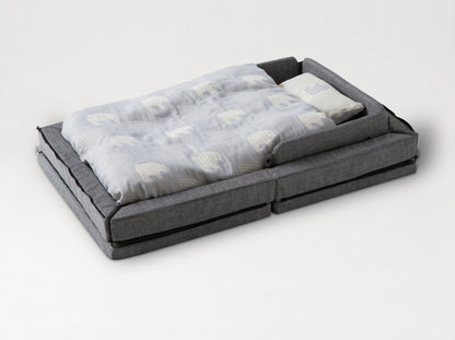 The färska Compact Bed Free in Melange Gray, made up with its quilt and pillow, sides raised 