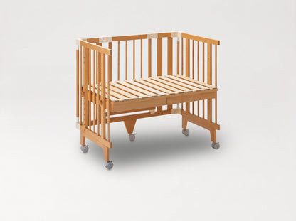Creative Cot in co-sleeping mode: slatted base raised to the parent bed, one long side removed, on castors