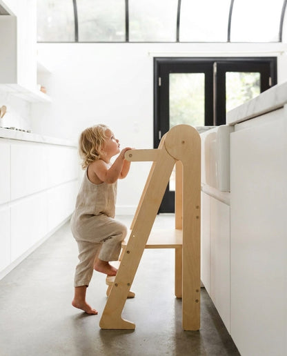 Toddler climbing the steps of a learning tower independently