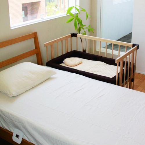 Baby cot secured alongside an adult bed, anchor plate under the mattress