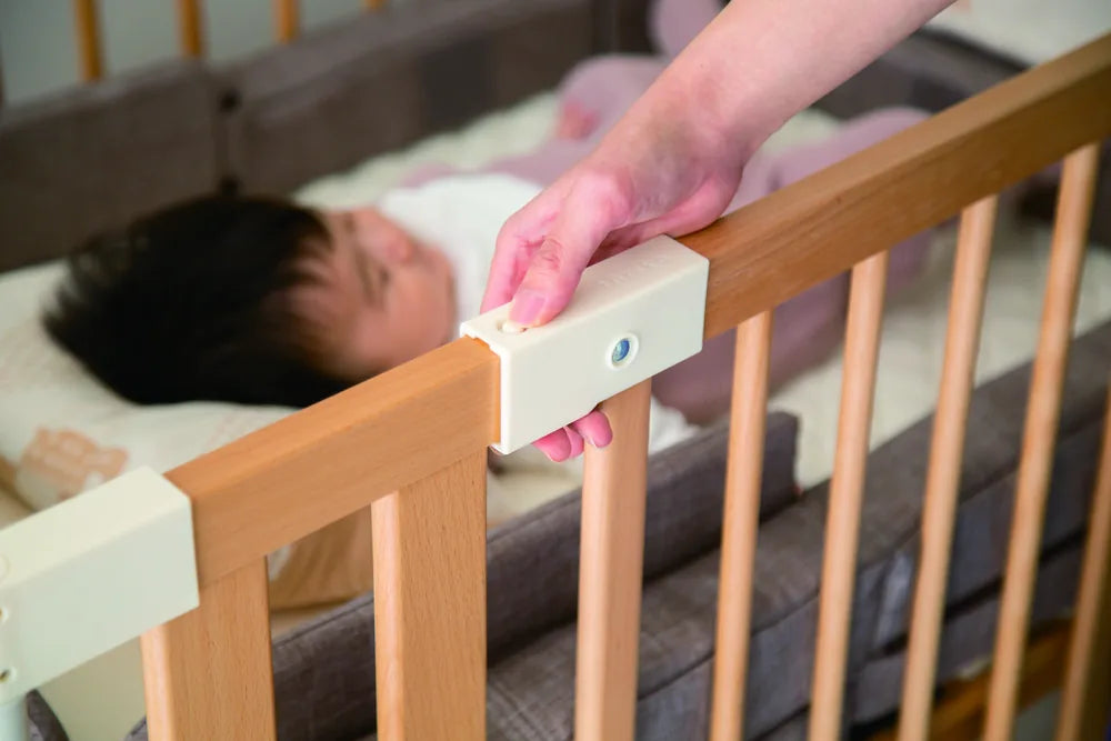 An adult's hand opening the Double Lock on the Creative Cot door