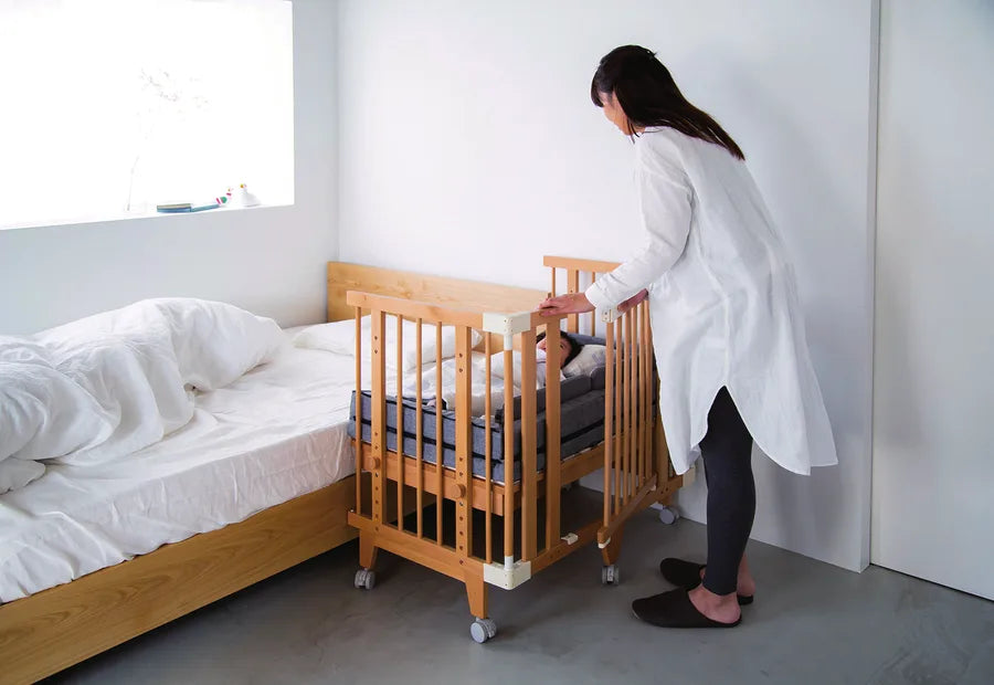 A mother opening the Creative Cot door beside an adult bed