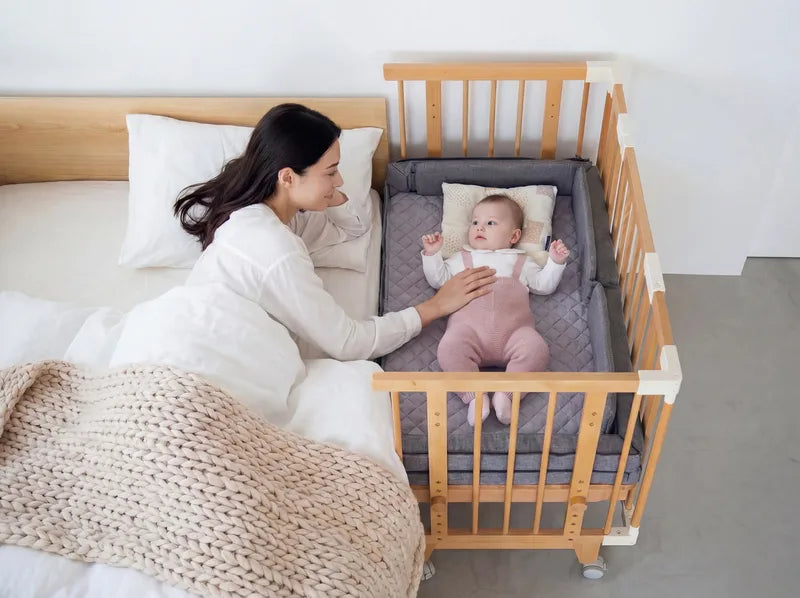 The Creative Cot right up against an adult bed, mum beside her baby
