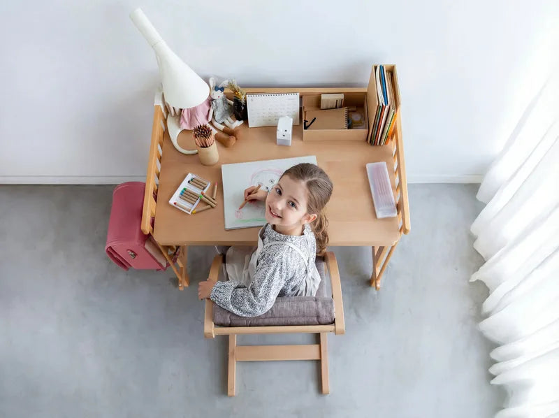 A child drawing at the Creative Cot desk, top view