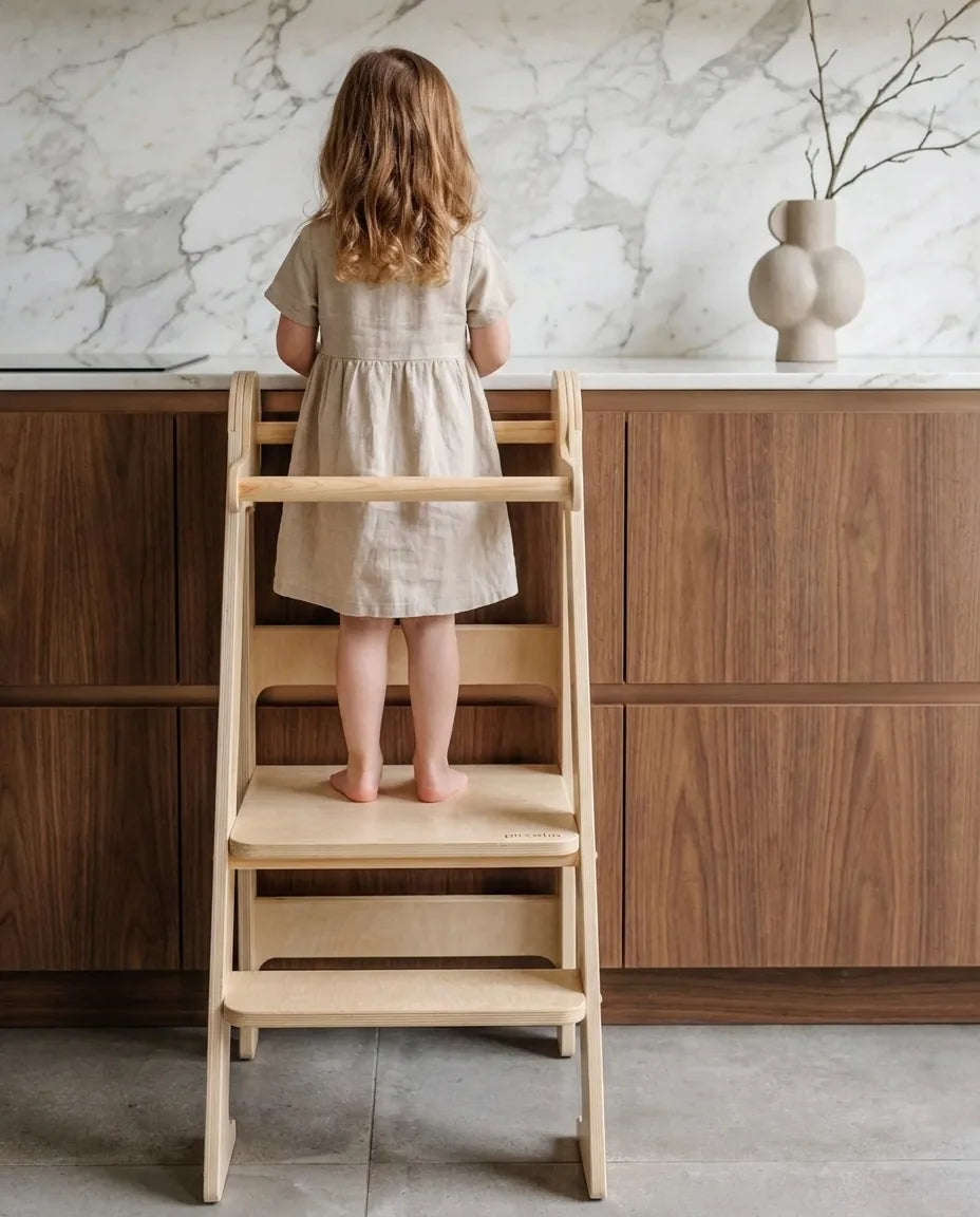 Child on a learning tower reaching the kitchen counter