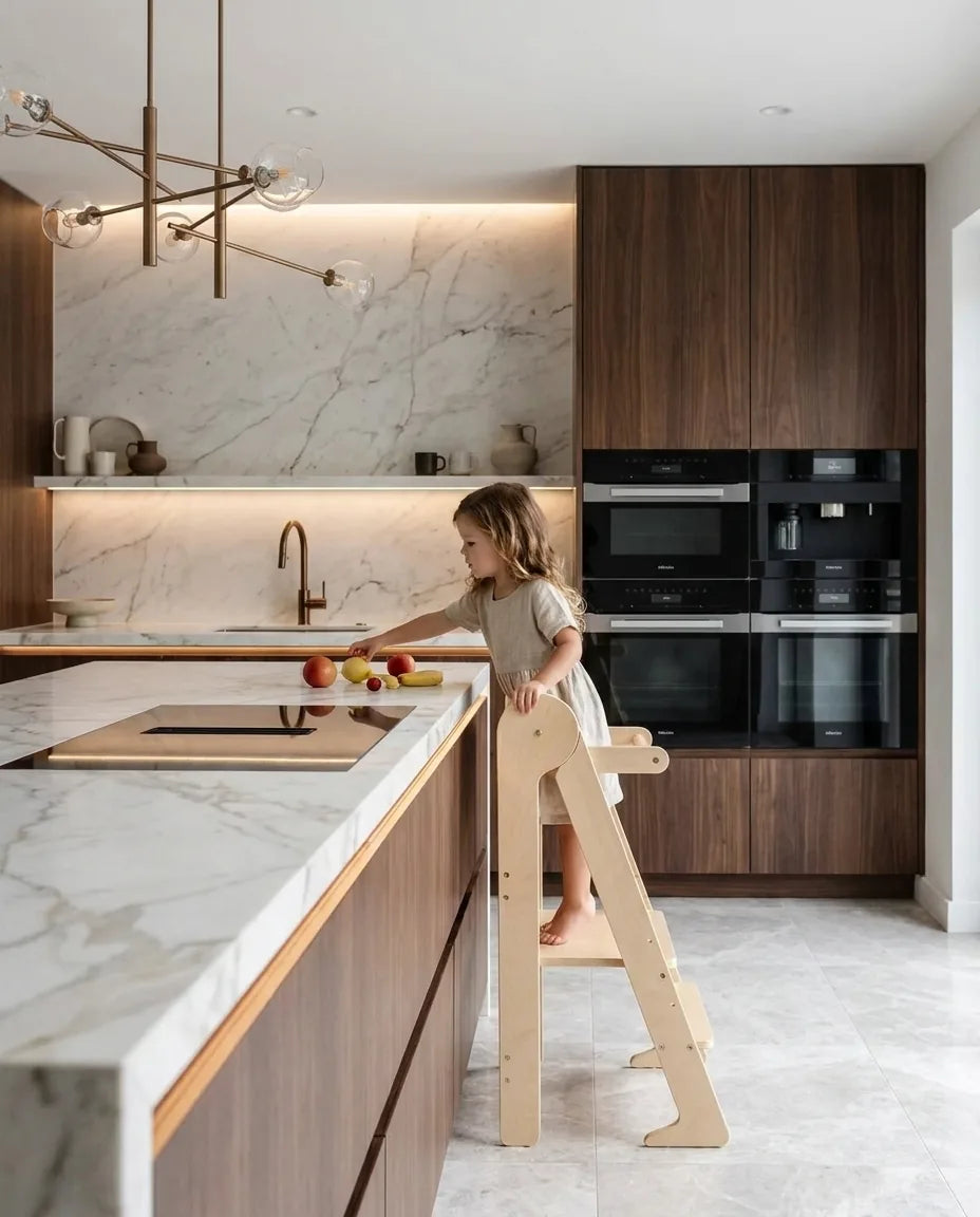 Child on a learning tower reaching for fruit on a kitchen island