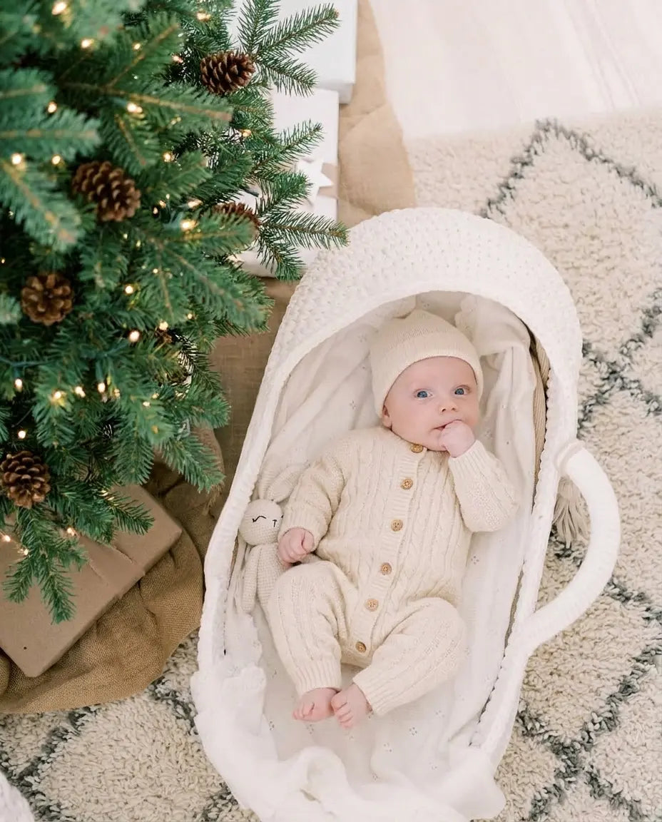 Newborn sleeping in a beige handwoven basket beside a window